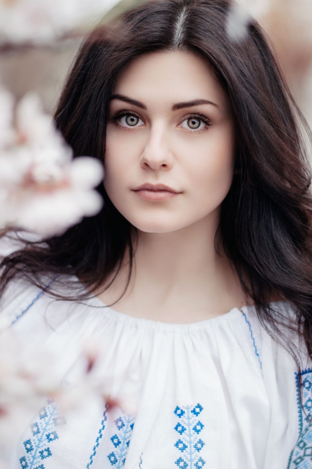 Woman with clear skin poses with flowers in the foreground