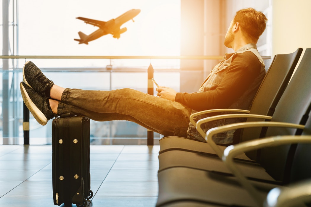 Man watches airplane take off through a window at his gate