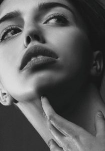 Close up black and white photo of woman touching her neck