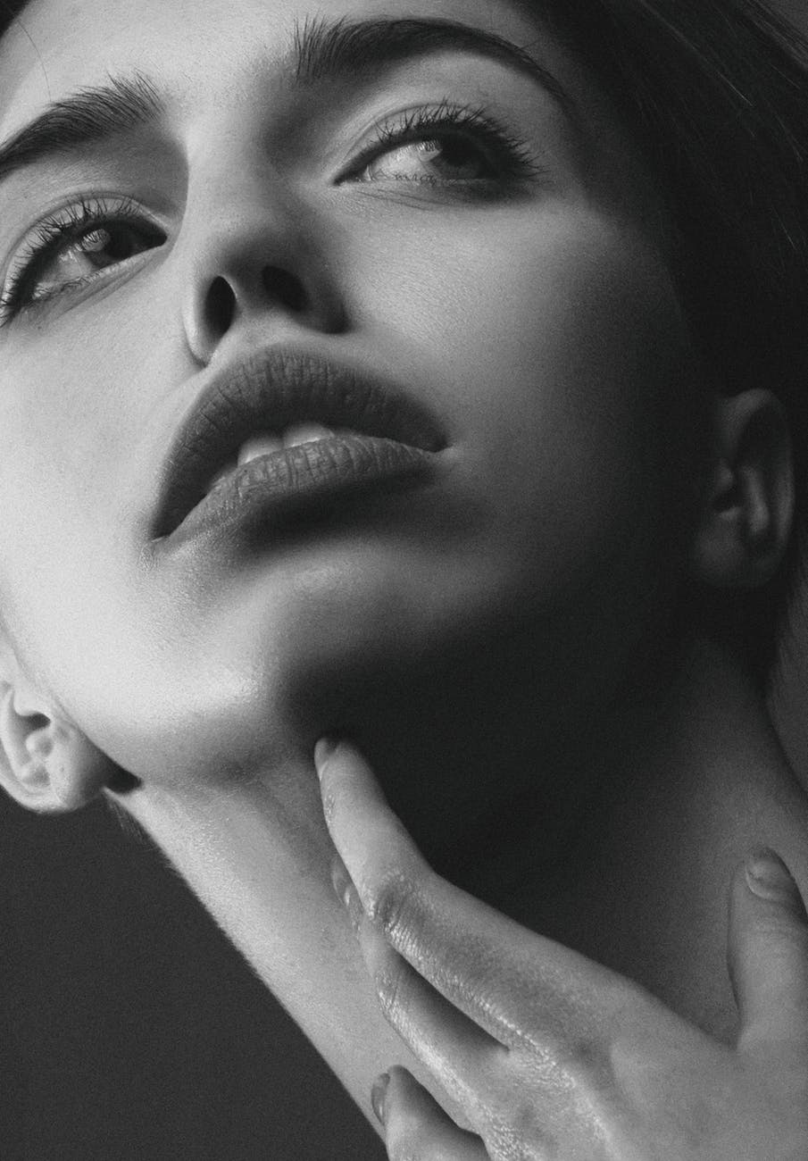 Close up black and white photo of woman touching her neck